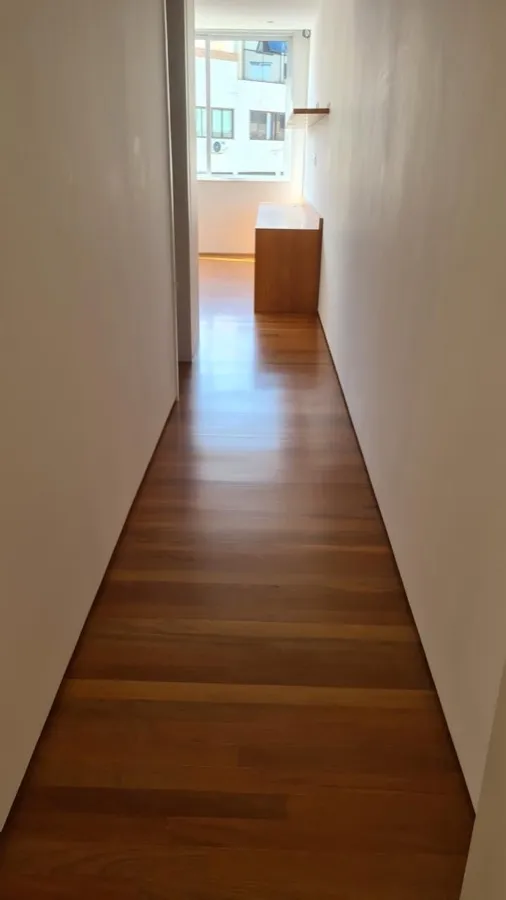 Apartamento com piso de madeira — corredor. Obra da Alta Construtora.