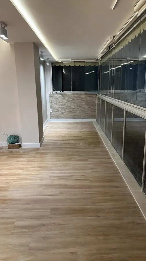 Apartamento com piso vinílico — varanda envidraçada. Obra da Alta Construtora.